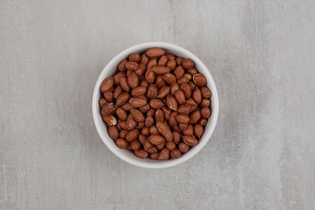 Heap of fresh peanuts in white bowl.