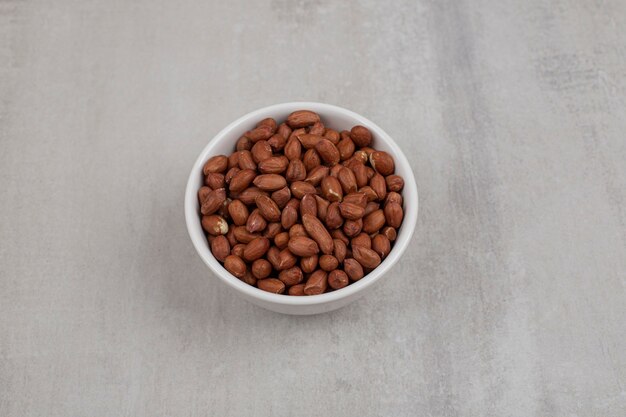 Heap of fresh peanuts in white bowl.