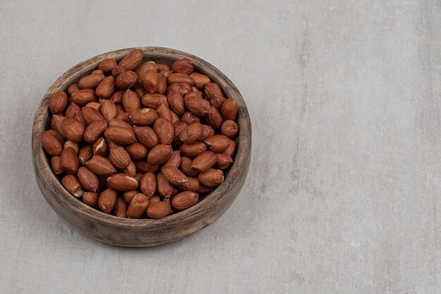 Heap of fresh peanuts in wooden bowl.