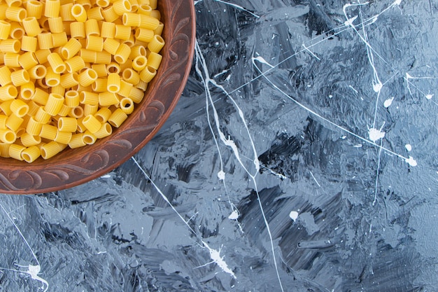 Бесплатное фото Куча сырых макаронных изделий rigate пипетки в миске на мраморной предпосылке.