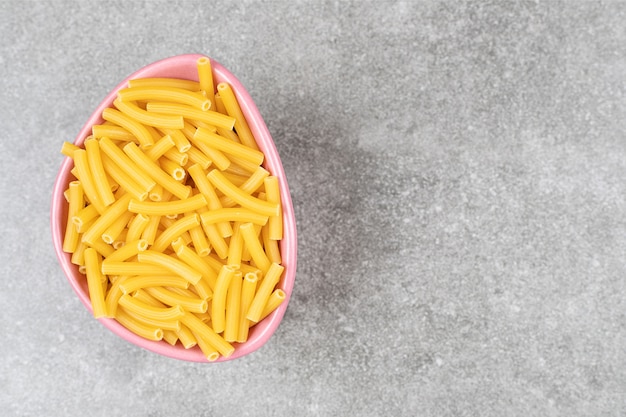 Heap of raw macaroni in pink bowl