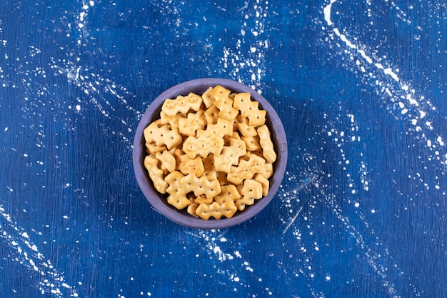 Free photo heap of salty small crackers placed in blue bowl.