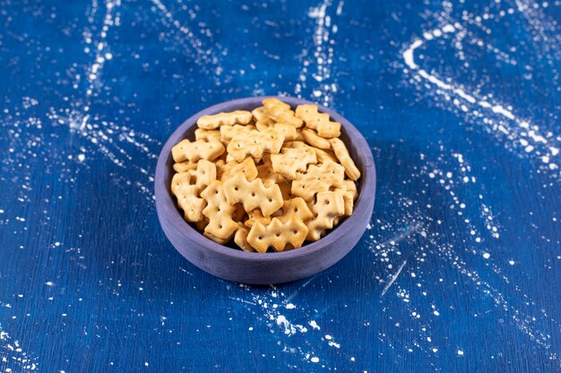 Heap of salty small crackers placed in blue bowl