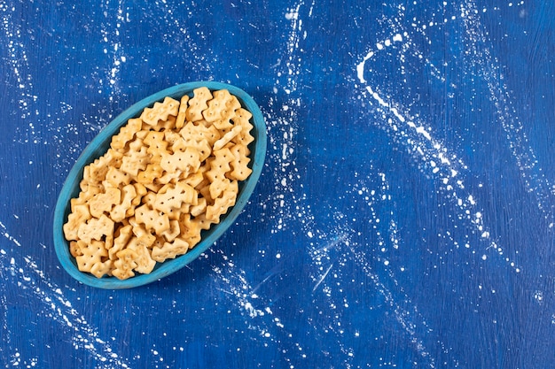 Heap of salty small crackers placed on blue plate