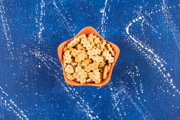 Heap of salty small crackers placed in orange bowl