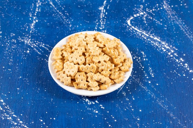 Heap of salty small crackers placed on white plate