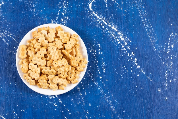 Mucchio di piccoli cracker salati disposti sul piatto bianco