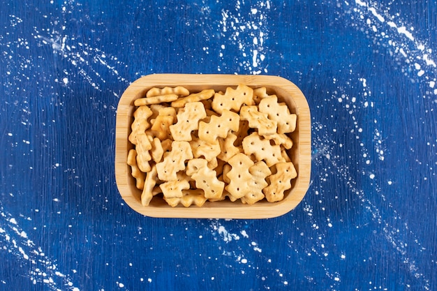 Heap of salty small crackers placed in wooden bowl.