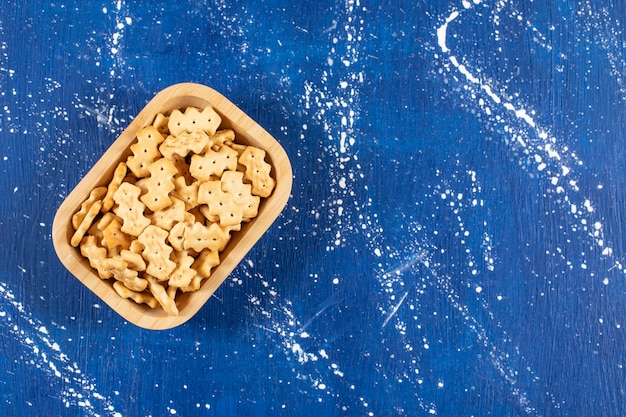 Heap of salty small crackers placed in wooden bowl. 