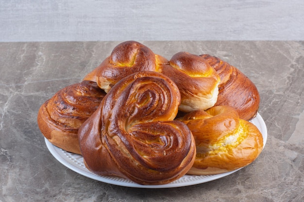 Heap of sweet buns on a platter on marble background. High quality photo