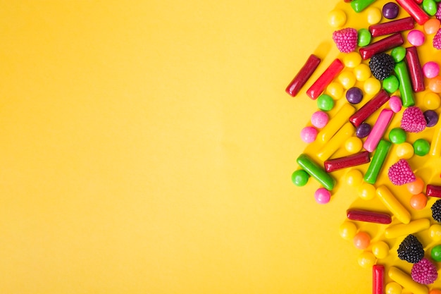 Heap of tasty candies on yellow background