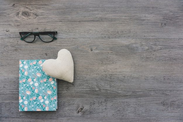 Heart, book and glasses on wooden surface