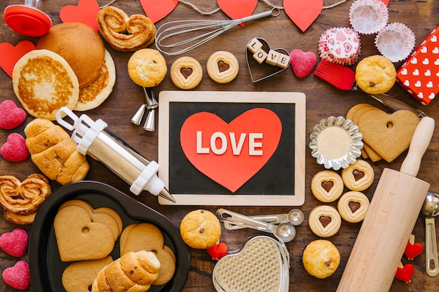 Heart and chalkboard amidst bakeware and pastry