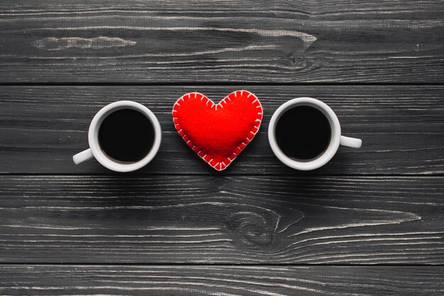 Heart between coffee cup on gray background