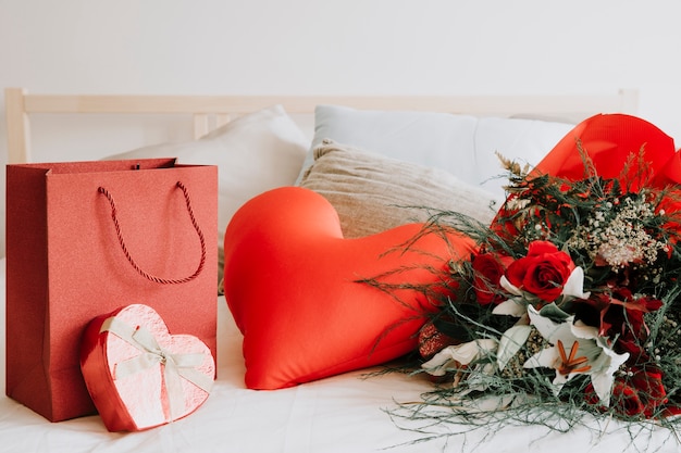 Foto gratuita cuscino a forma di cuore tra regalo e bouquet