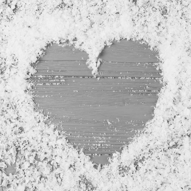 Free photo heart between decorative snow on wooden desk