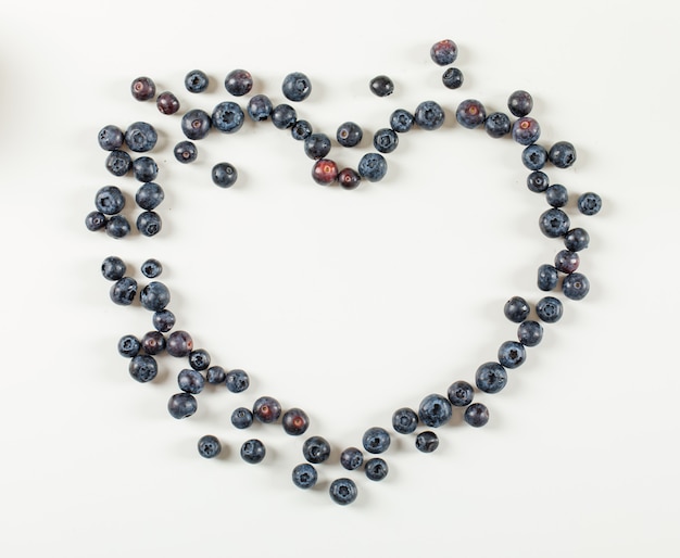 Heart made of blueberries on a white surface. flat lay.