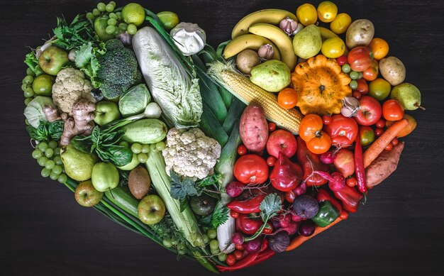 Heart made of fresh vegetables and fruit on wooden background