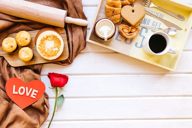 Foto gratuita cuore e rosa vicino al vassoio con il cibo