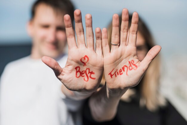 Heart shape and best friends text on couple's hand