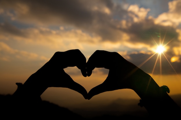 Heart shape from two hand with sunrise background. 