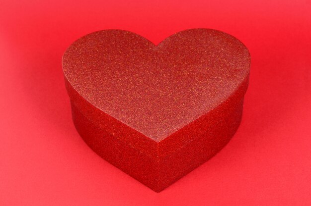 Подарочная коробка блеска формы сердца на красной бумажной предпосылке.