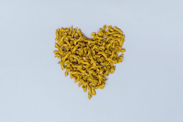 Heart shape made from italian uncooked pasta on gray background 