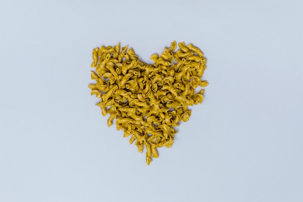 Heart shape made from italian uncooked pasta on gray background 