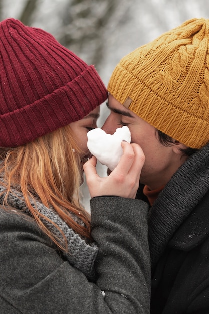 Foto gratuita a forma di cuore fatto da neve e coppia