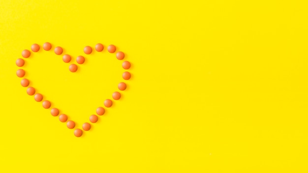 無料写真 黄色の背景に丸薬で作られた心臓の形