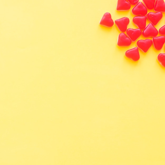 Heart shape red candies on the corner of yellow backdrop