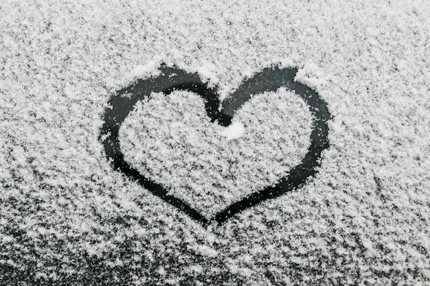 Free photo heart shape on snowy glass during winter day