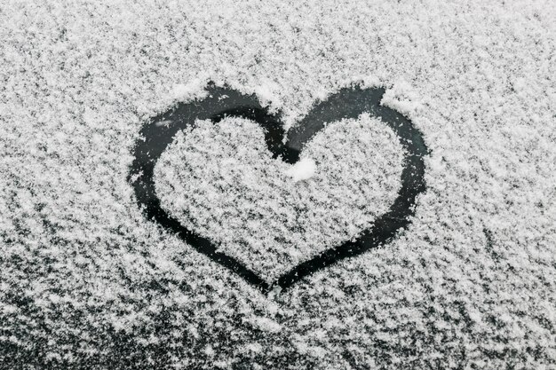 Форма сердца на снежном стекле в зимний день