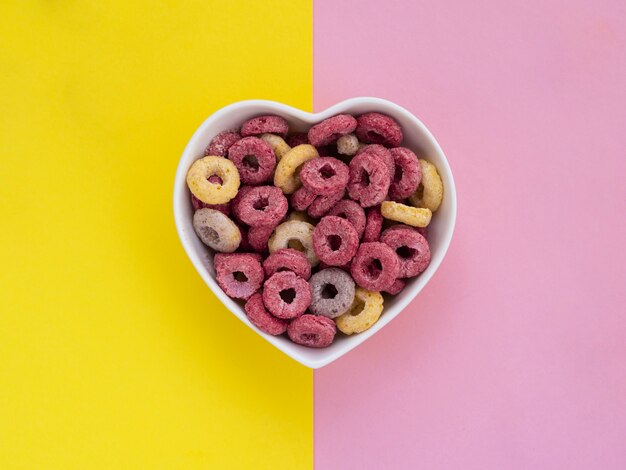 Чаша в форме сердца, наполненная розовыми и желтыми фруктовыми петлями