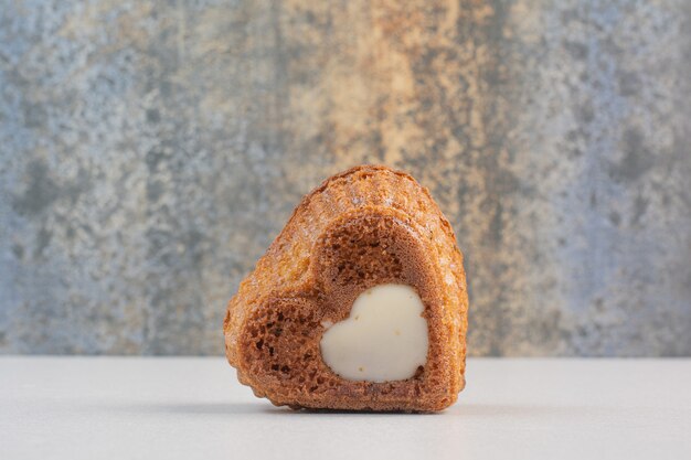 Heart shaped cake with cream on white table.