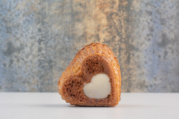 Торт в форме сердца со сливками на белом столе.