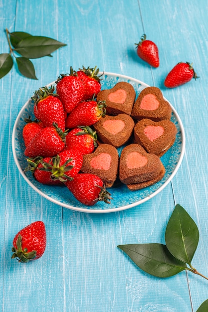 Шоколадное и клубничное печенье в форме сердца со свежей клубникой, вид сверху