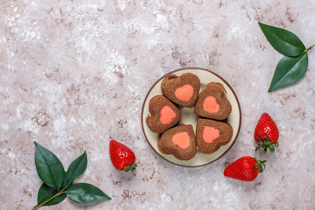 Heart shaped chocolate and strawberry cookies with fresh strawberries, top view