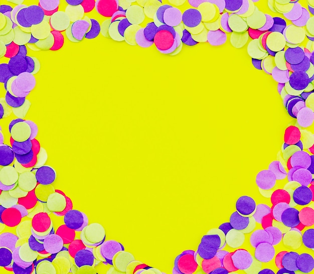 Heart shaped colorful confetti on yellow background