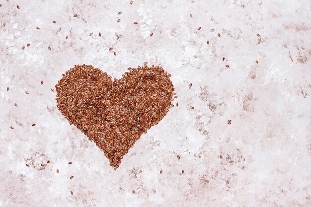 Heart shaped flax seeds on concrete background with space for copy,top view