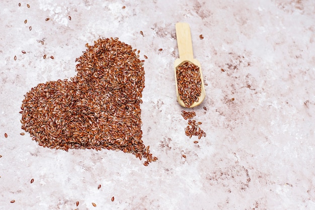Heart shaped flax seeds on concrete background with space for copy,top view
