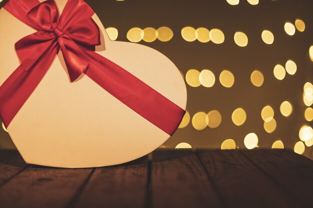 Heart-shaped gift box on a wooden table with a bokeh background