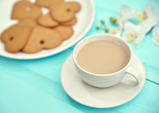 Heart shaped gingerbread cookie on gray plate with cup of coffee top view Old wooden table