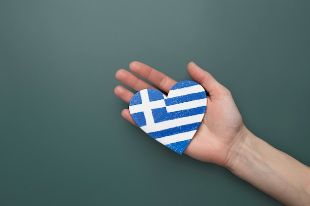Флаг греции в форме сердца держится в руках