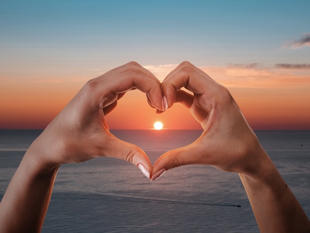 Foto gratuita mani a forma di cuore su un tramonto