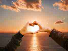 Free photo heart-shaped hands on a sunset