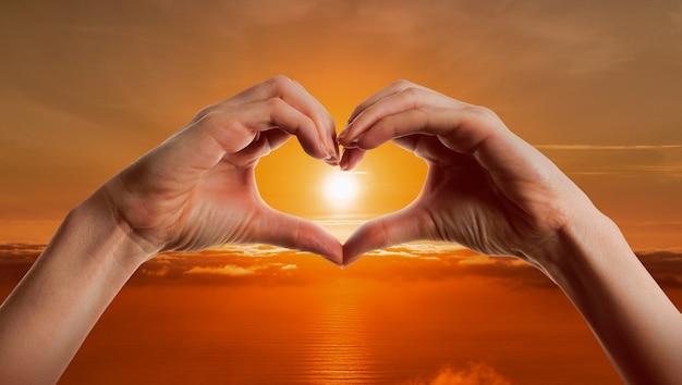 Free photo heart-shaped hands on a sunset