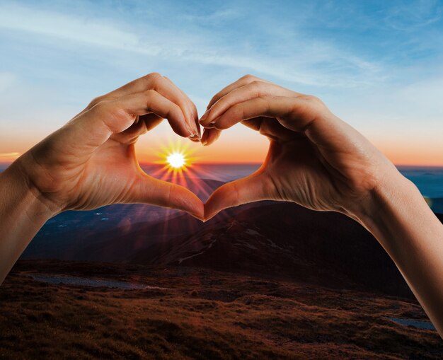 Heart-shaped hands on a sunset