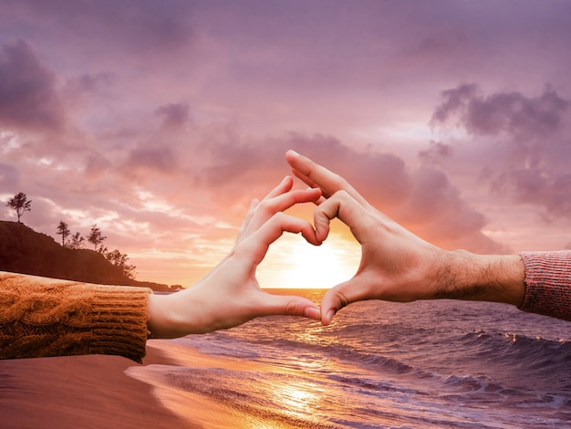 Heart-shaped hands on a sunset