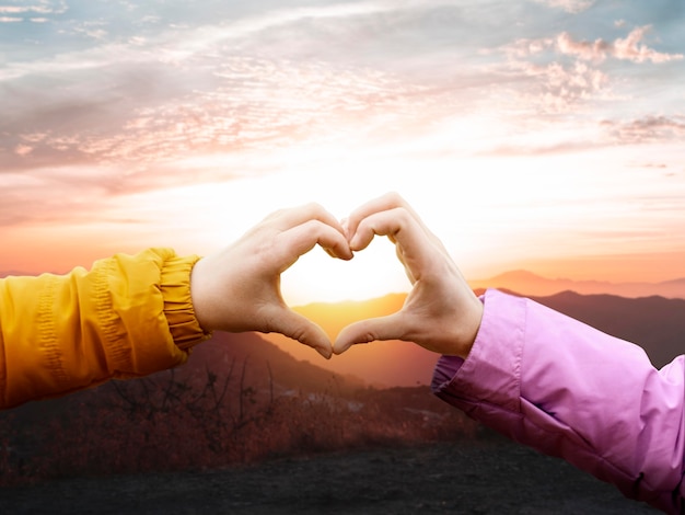 Heart-shaped hands on a sunset